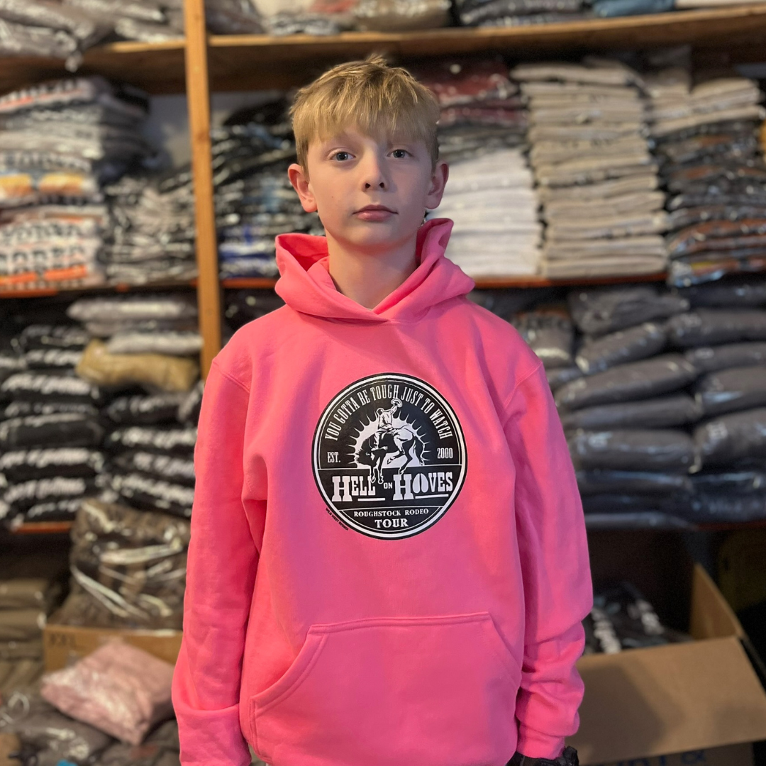 Child wearing a Hell on Hooves Youth Hoodie in Neon Pink with Roughstock Rodeo Tour front graphic.